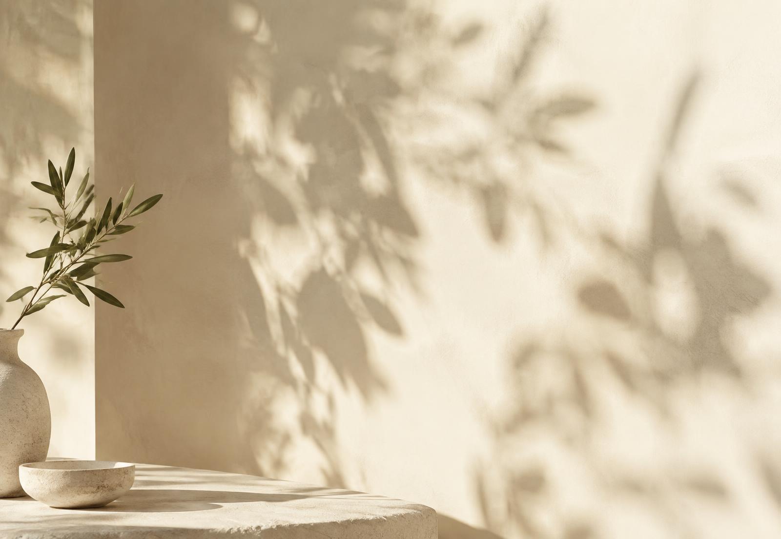 Soft morning light and leaf shadows on a cream wall